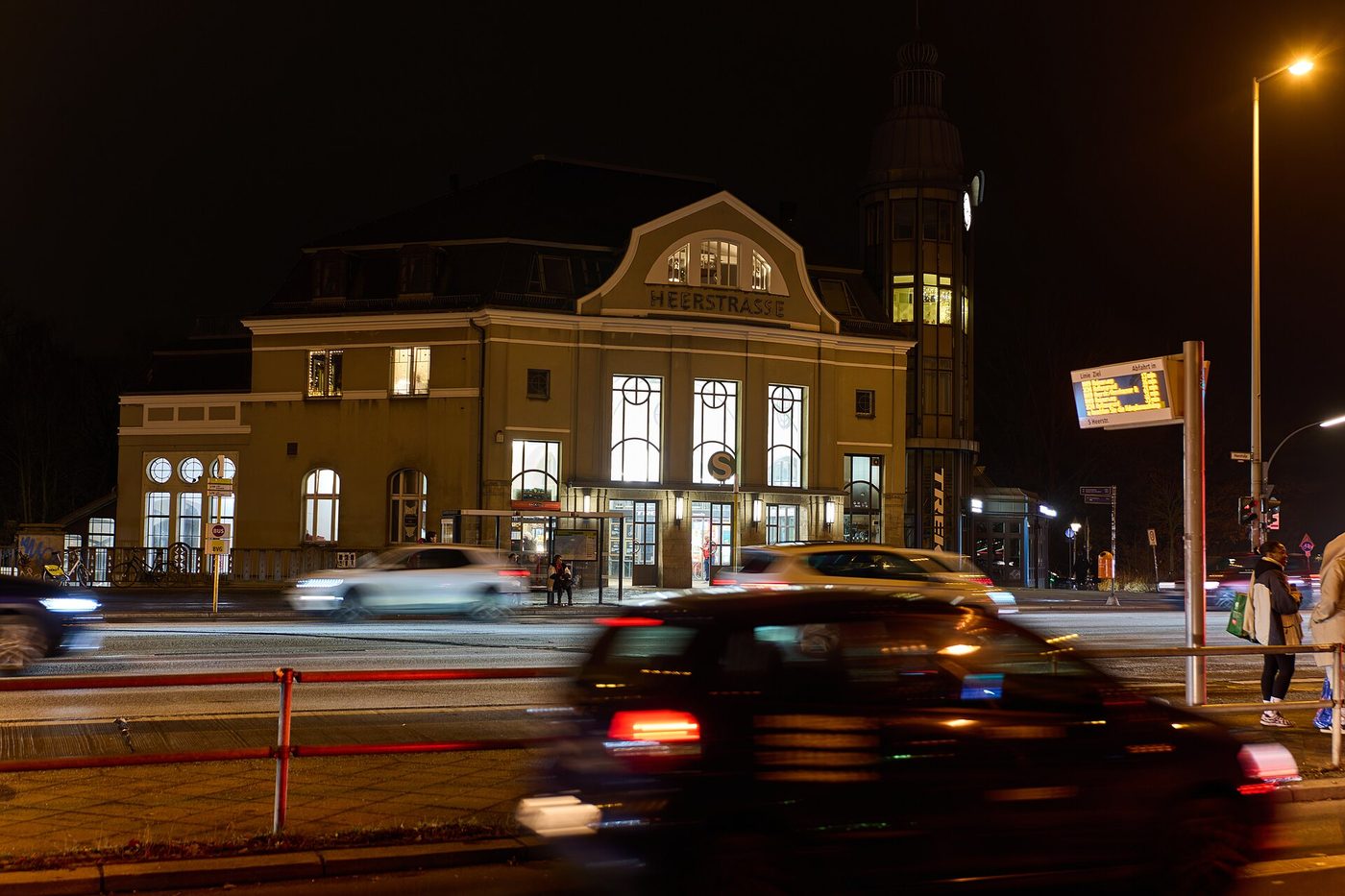 A lit historic station building in Berlin at night, a car passing in front