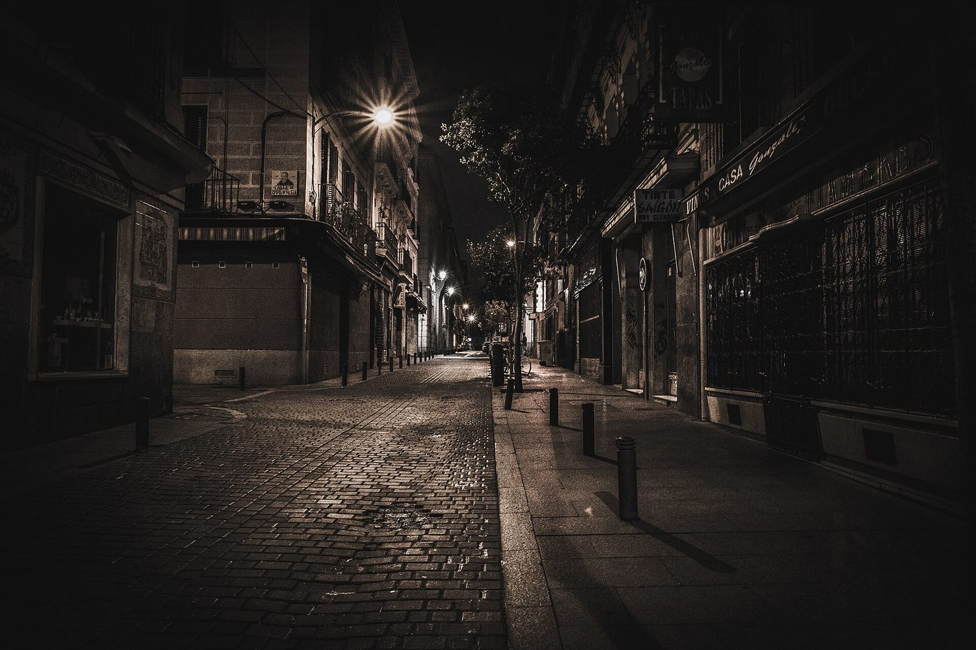 An empty cobblestone street at night under street lamps
